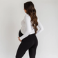 Pregnant woman wearing black supportive maternity leggings with high-rise waistband and white long-sleeve top.